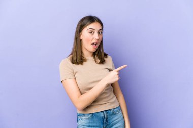 Beyaz bir kadın gülümsüyor ve boş alanda bir şeyler gösteriyor..