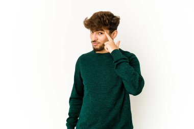 Beyaz arka planda genç bir Arap, parmağıyla tapınağı işaret ediyor, düşünüyor ve bir göreve odaklanıyor..