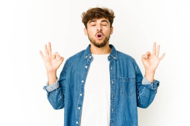 Beyaz arka plandaki genç Arap adam yorucu bir günün ardından rahatlıyor. Yoga yapıyor..