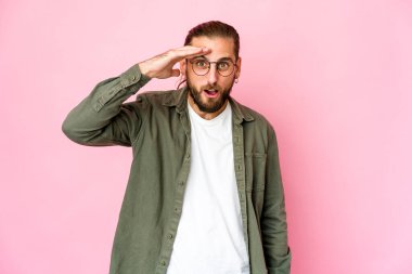 Uzun saçlı genç adam yüksek sesle bağırıyor, gözleri açık ve elleri gergin tutuyor..