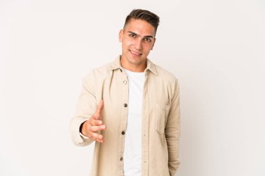 Beyaz tenli yakışıklı adam kameraya elini uzatarak selam veriyor..