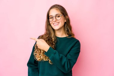 Beyaz bir kadın gülümsüyor ve boş alanda bir şeyler gösteriyor..