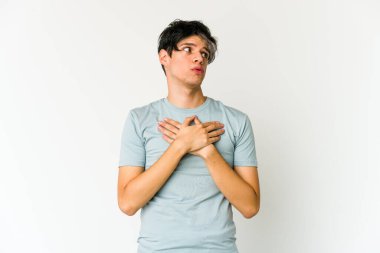 Genç, sıska İspanyol bir adam, dost canlısı bir ifadeye sahip, avuçlarını göğsüne bastırıyor. Aşk konsepti.