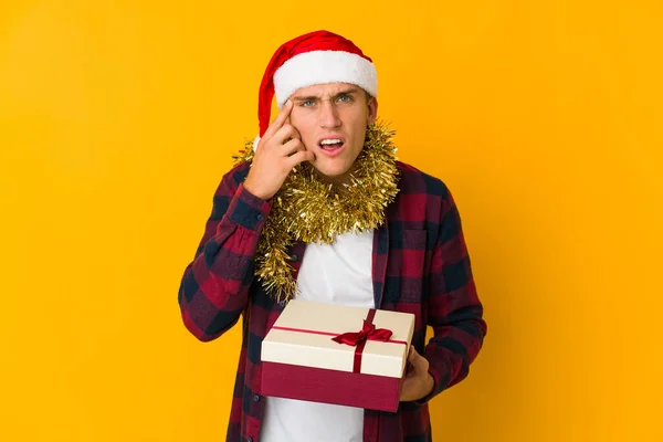 若いですCaucasian男とともにクリスマス帽子保持していますプレゼント隔離上の黄色の背景ショックを受けて 彼女は重要な会議を覚えています — ストック写真