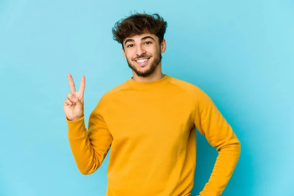 Νεαρός Άραβας Μπλε Φόντο Χαρούμενος Και Ανέμελος Δείχνοντας Ένα Σύμβολο — Φωτογραφία Αρχείου