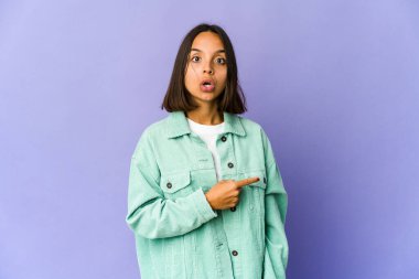 Genç melez kadın gülümsüyor ve boş alanda bir şeyler gösteriyor..