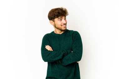 Beyaz arka plandaki genç Arap adam kollarını kavuşturarak gülümsüyor..