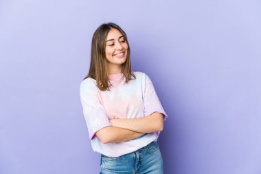 Genç beyaz kadın kollarını kavuşturarak gülümsüyor..