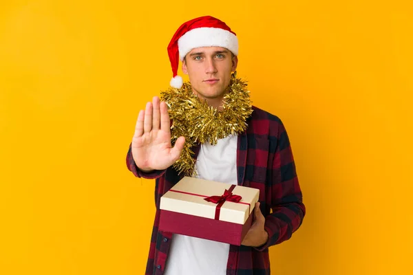 Junger Kaukasischer Mann Mit Weihnachtsmütze Hält Ein Geschenk Isoliert Auf — Stockfoto