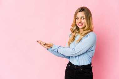 Genç, beyaz, sarışın bir kadın kulaklarını parmaklarıyla kapatıyor. Yüksek sesli bir ortam yüzünden stresli ve çaresiz..