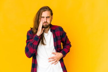 Uzun saçlı genç adam yanakları şişiriyor, yorgun bir ifade takınıyor. Yüz ifadesi kavramı.