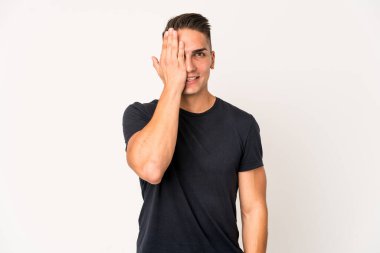 Beyaz tenli yakışıklı bir adam izole edilmiş. Yüzünün yarısını palmiyeyle kaplayarak eğleniyor..