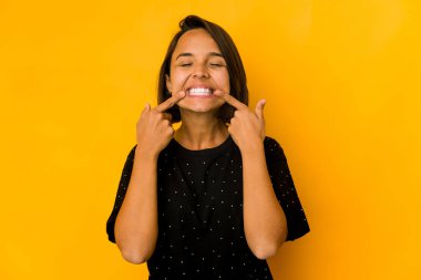Sarı tebessümlerle izole edilmiş genç İspanyol kadın, parmaklarını ağzına doğrultuyor..