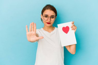 Genç, sıska bir Arap kızın elinde sevgililer günü kartı var. Elini uzatmış, dur işareti gösteriyor..