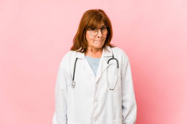Middle age caucasian doctor woman isolated confused, feels doubtful and unsure.