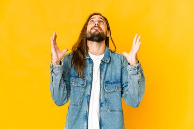 Uzun saçlı genç adam kahkahalarla gülüyor elini göğsüne koyuyor..