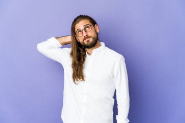 Uzun saçlı genç adam başının arkasına dokunuyor, düşünüyor ve bir seçim yapıyor..