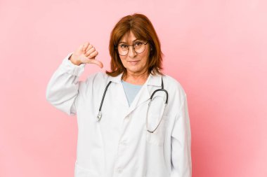 Middle age caucasian doctor woman isolated showing a dislike gesture, thumbs down. Disagreement concept.