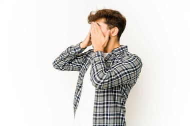 Beyaz arka plandaki genç Arap adam elleriyle gözlerini kapatmaktan korkuyor..