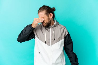 Uzun saçlı, başı ağrıyan, yüzüne dokunan bir genç..