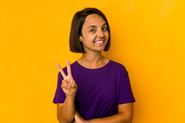 Sarıda izole edilmiş genç İspanyol kadın iki numarayı parmaklarıyla gösteriyor..