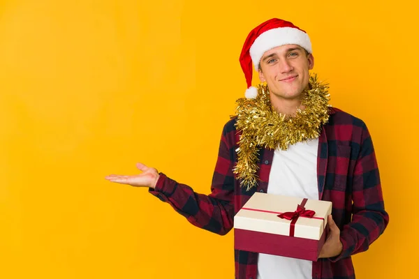 Молодий Білий Чоловік Різдвяним Капелюхом Тримає Подарунок Ізольовано Жовтому Тлі — стокове фото