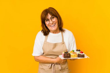 Orta yaşlı beyaz aşçı kadın gülüyor ve eğleniyor..