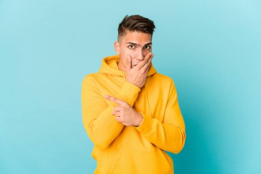 Genç, beyaz, yakışıklı bir adam tek başına, yan tarafı işaret ediyor.