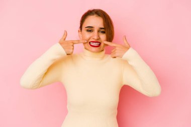 Genç Arap melez kadın gülümsüyor, parmaklarıyla ağzını işaret ediyor..