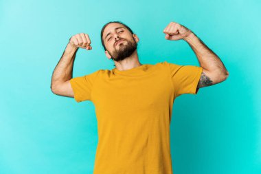 Uzun saçlı genç adam güçlü bir hareket sergiliyor kollarıyla, gücün sembolü.