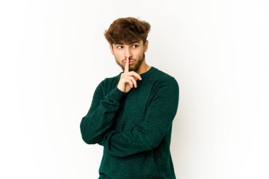 Beyaz arka planda genç bir Arap şüpheli ve şüpheci bir ifadeyle yana bakıyor..