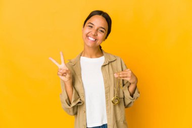 İki numarayı parmaklarıyla gösteren cep saatini tutan genç İspanyol kadın..