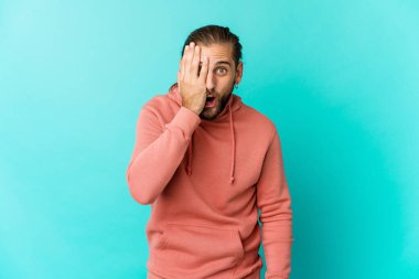 Uzun saçlı genç adam yüzünün yarısını avuç içiyle örterek eğleniyor..