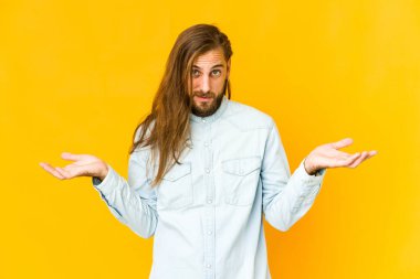 Uzun saçlı genç adam şüpheli görünüyor ve sorgulama sırasında omuzlarını silkiyor..