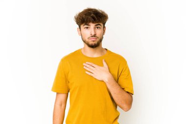 Beyaz arka planda genç bir Arap yemin ediyor, elini göğsüne koyuyor..
