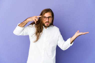 Uzun saçlı genç adam elinde bir ürünü tutuyor ve gösteriyor..