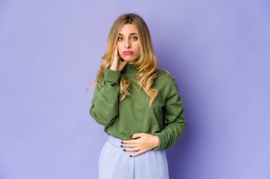 Beyaz tenli sarışın kadın yanaklarına sakso çekiyor, yorgun bir ifade takınıyor. Yüz ifadesi kavramı.