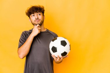 Genç futbolcu Hintli adam şüpheli ve şüpheci bir ifadeyle yana bakıyor..