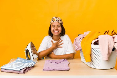 Elbiseleri ütüleyen genç İspanyol kadın kahkahalarla kahkahalar atıyor..