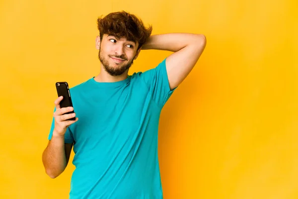 Joven Indio Sosteniendo Teléfono Tocando Parte Posterior Cabeza Pensando Haciendo —  Fotos de Stock