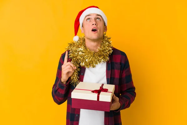 Jovem Caucasiano Com Chapéu Natal Segurando Presente Isolado Fundo Amarelo — Fotografia de Stock