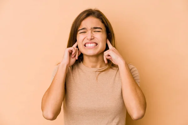 Young skinny caucasian teenager girl covering ears with fingers, stressed and desperate by a loudly ambient.