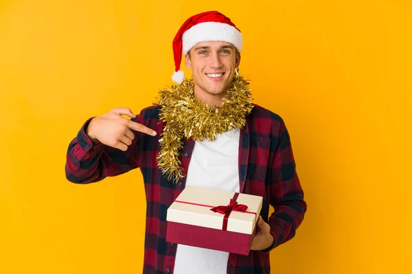 若いですCaucasian男とともにクリスマス帽子保持していますプレゼント隔離された上に黄色の背景かじる爪 神経と非常に不安 — ストック写真