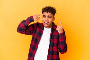 Genç Afro-Amerikalı kıvırcık adam mor üzerine izole edilmiş işaret parmağıyla hayal kırıklığı jesti yapıyor..