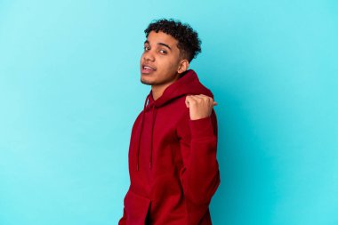 Genç Afro-Amerikan kıvırcık adamı mavi noktalarda izole edilmiş, başparmak uzakta, gülüyor ve kaygısız..