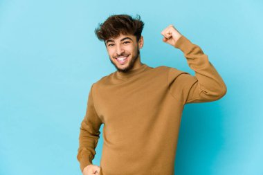 Mavi arka planda genç bir Arap tasasız ve heyecanlı tezahüratlar yapıyor. Zafer konsepti.