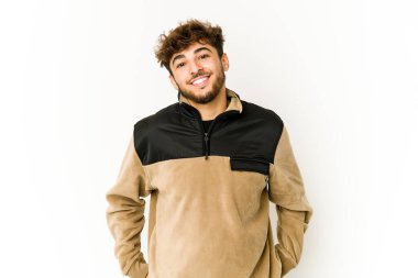 Beyaz arka plandaki genç Arap adam mutlu, güler yüzlü ve neşeli.