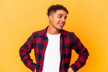 Genç Afro-Amerikalı kıvırcık adam Mor üzerine izole edilmiş mutlu bir şekilde gülüyor ve ellerini karnının üstünde tutarak eğleniyor..