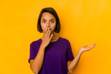 Sarı renkte izole edilmiş genç İspanyol kadın, avuç içinde kopya yeri tutmaktan etkilenmiş..