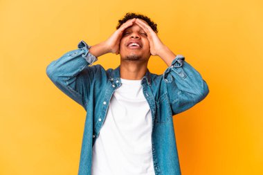 Genç Afro-Amerikan kıvırcık adamı, mor renkli kahkahalarla izole edilmiş, mutlu bir şekilde ellerini başının üstünde tutuyor. Mutluluk kavramı.